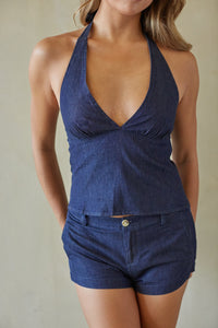Woman wearing a blue halter top and shorts set against a neutral background