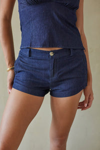 Person wearing a blue denim top and shorts on a neutral background