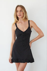 Woman wearing a black polka dot dress against a white background