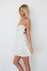 Woman wearing a strapless polka dot dress against a white background