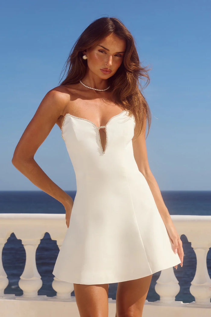 white-image | Woman in a white dress standing on a balcony with ocean view
