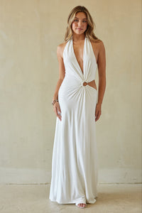 Woman wearing a white halter neck gown against a plain background