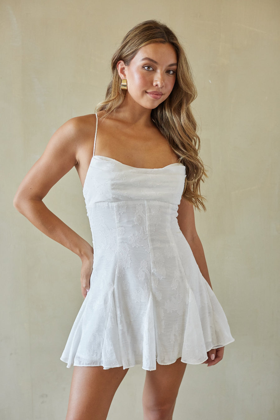 Woman wearing a white dress against a plain background