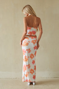 Woman wearing a strapless floral dress with a neutral background