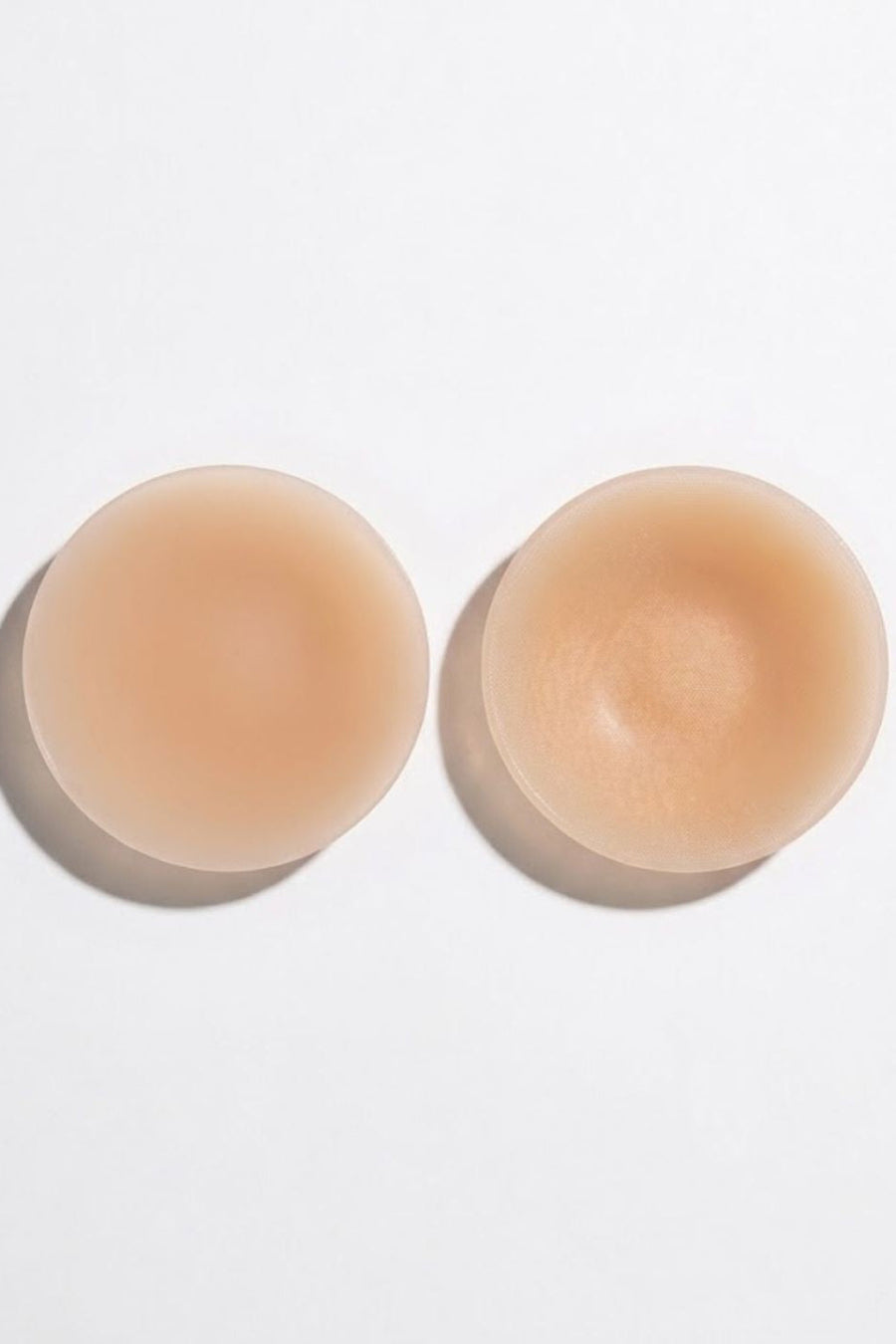 Two nude beige silicone adhesive nipple covers shown from top and side views on a clean white background.