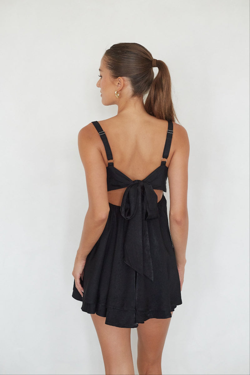 Woman wearing a black dress with cut-out back design on a white background