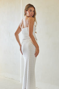 Woman wearing a white strapless dress against a plain background