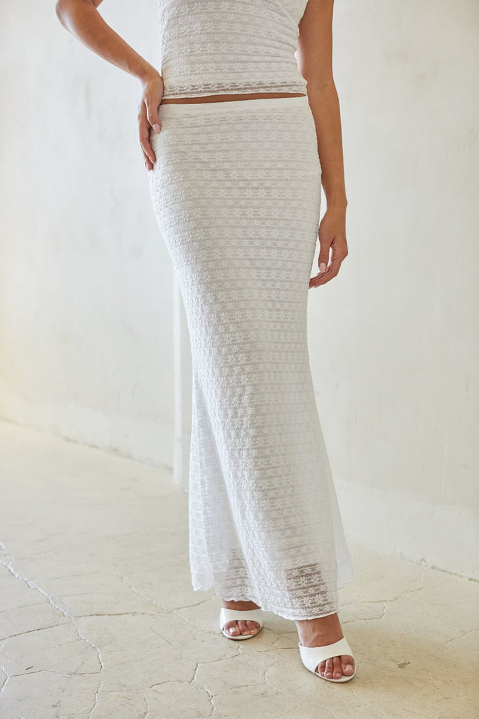 Woman wearing a textured white dress against a plain background