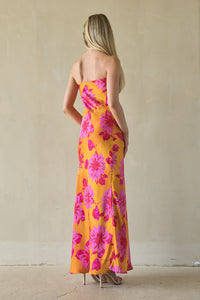 Woman wearing a strapless floral dress with pink and yellow flowers against a plain background