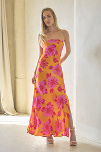 Woman wearing a yellow floral dress standing in a softly lit room.