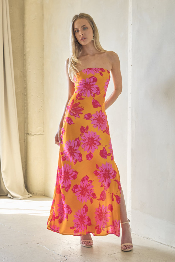 Woman wearing a yellow floral dress standing in a softly lit room.