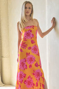 Woman wearing a vibrant floral dress in a sunlit room.