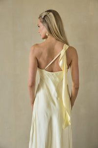 Woman wearing a light yellow slip dress against a beige background