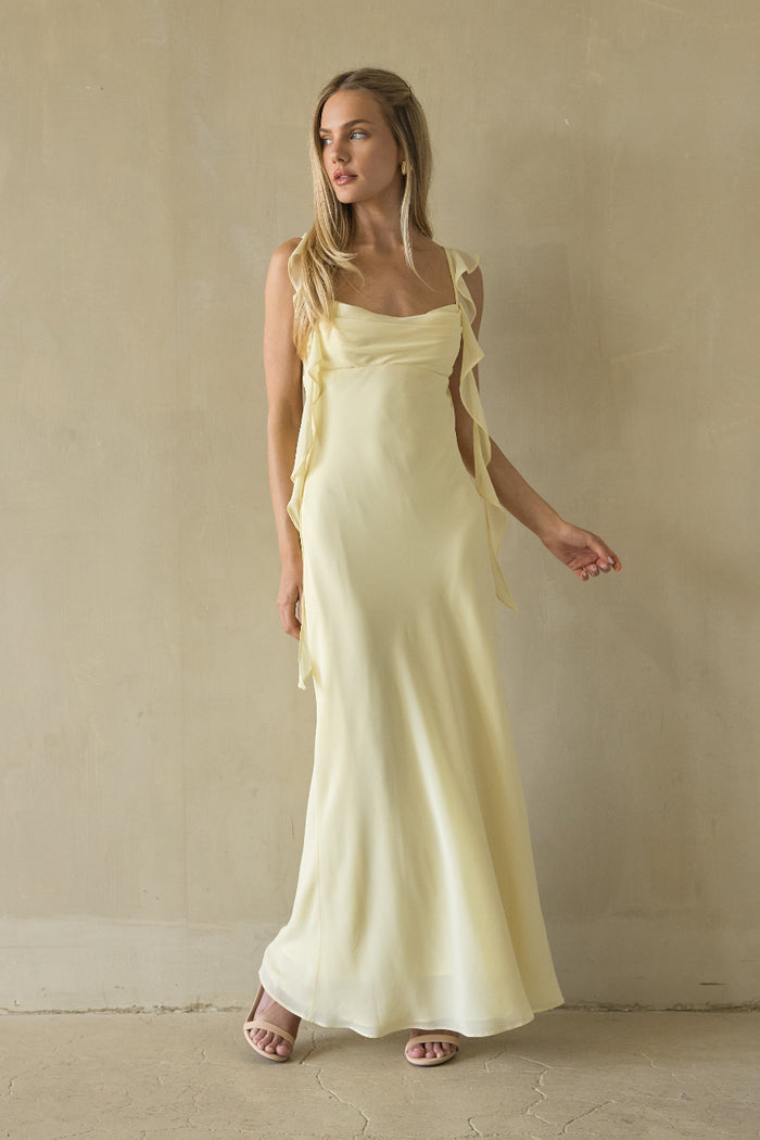 Woman wearing a long yellow dress against a plain background