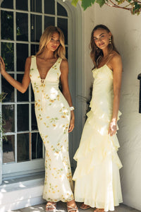 Two women in elegant dresses standing outdoors near a door.