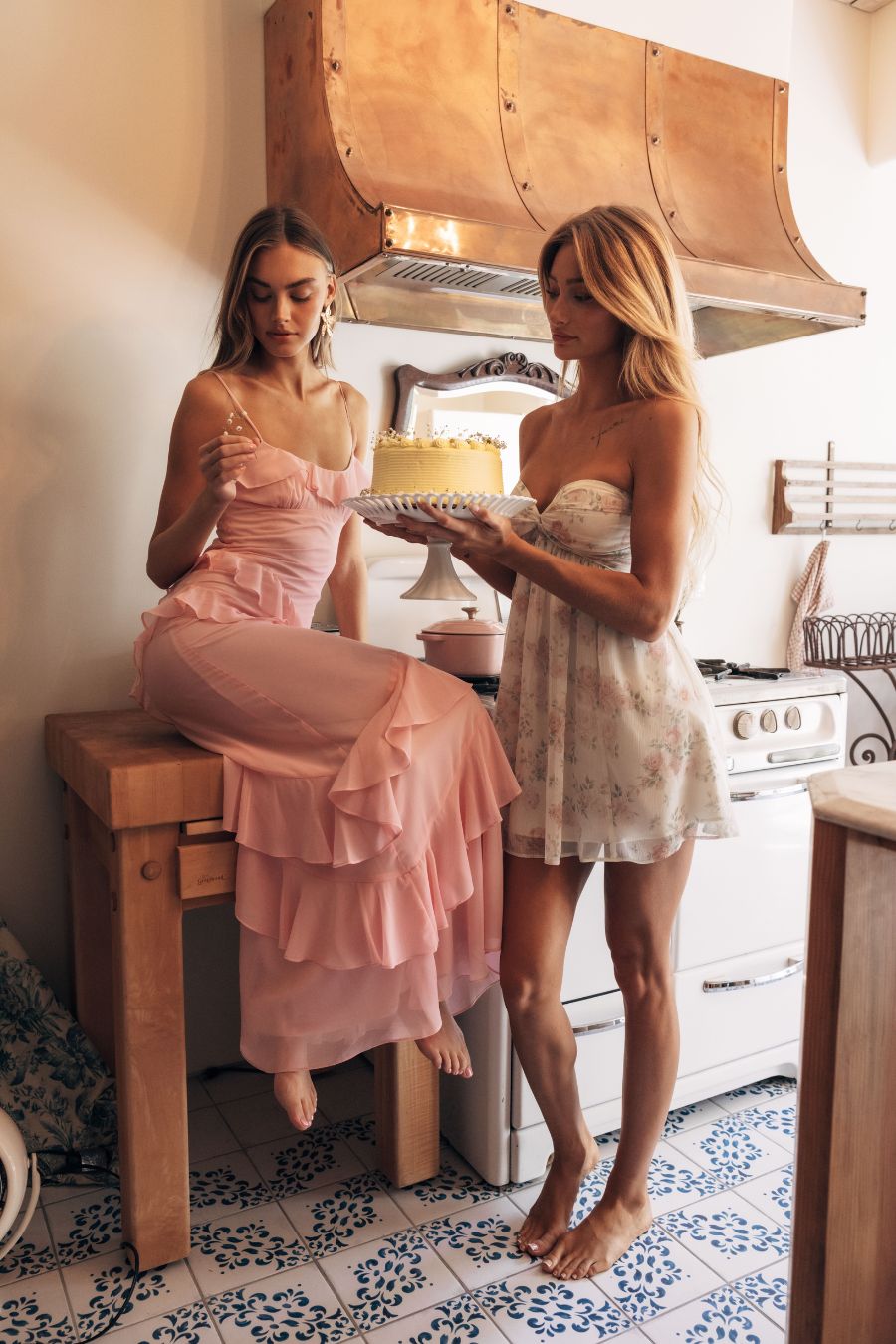 Two women in a kitchen with one holding a cake
