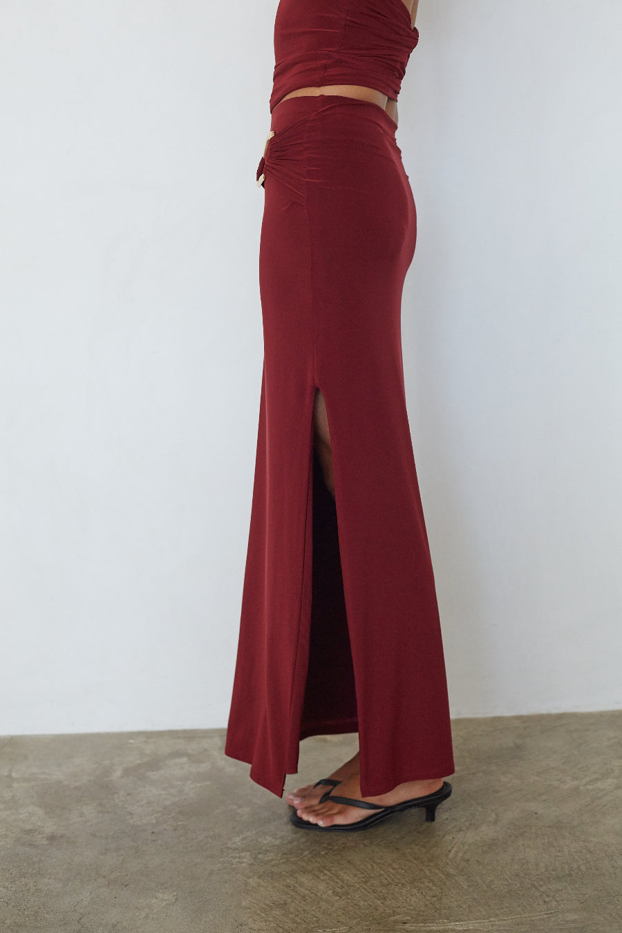 Burgundy ruched low waist maxi skirt, side profile view showing thigh-high slit