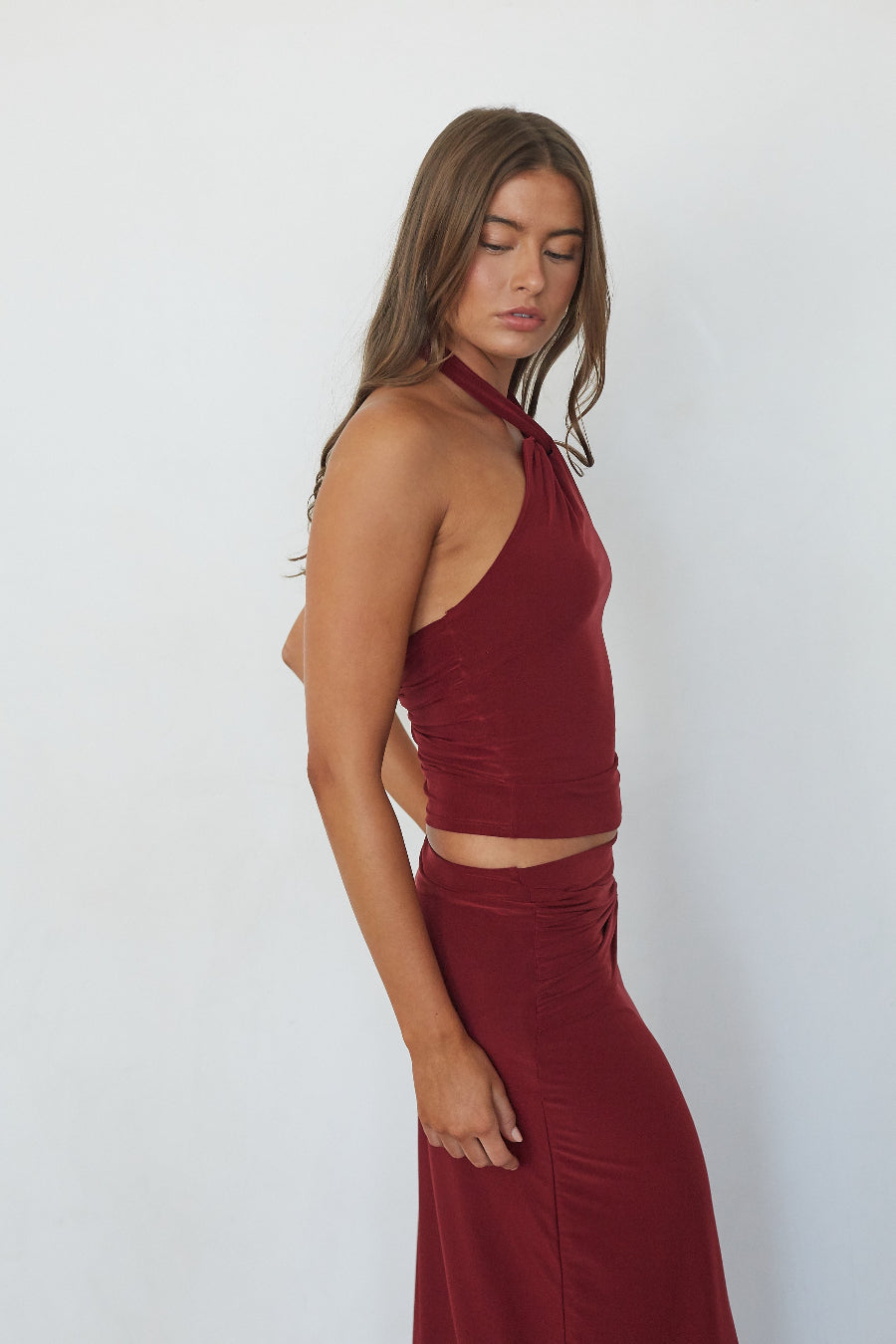 Burgundy twist halter crop top, side profile view on model
