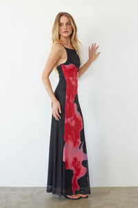 Woman wearing a black dress with red abstract patterns against a white background