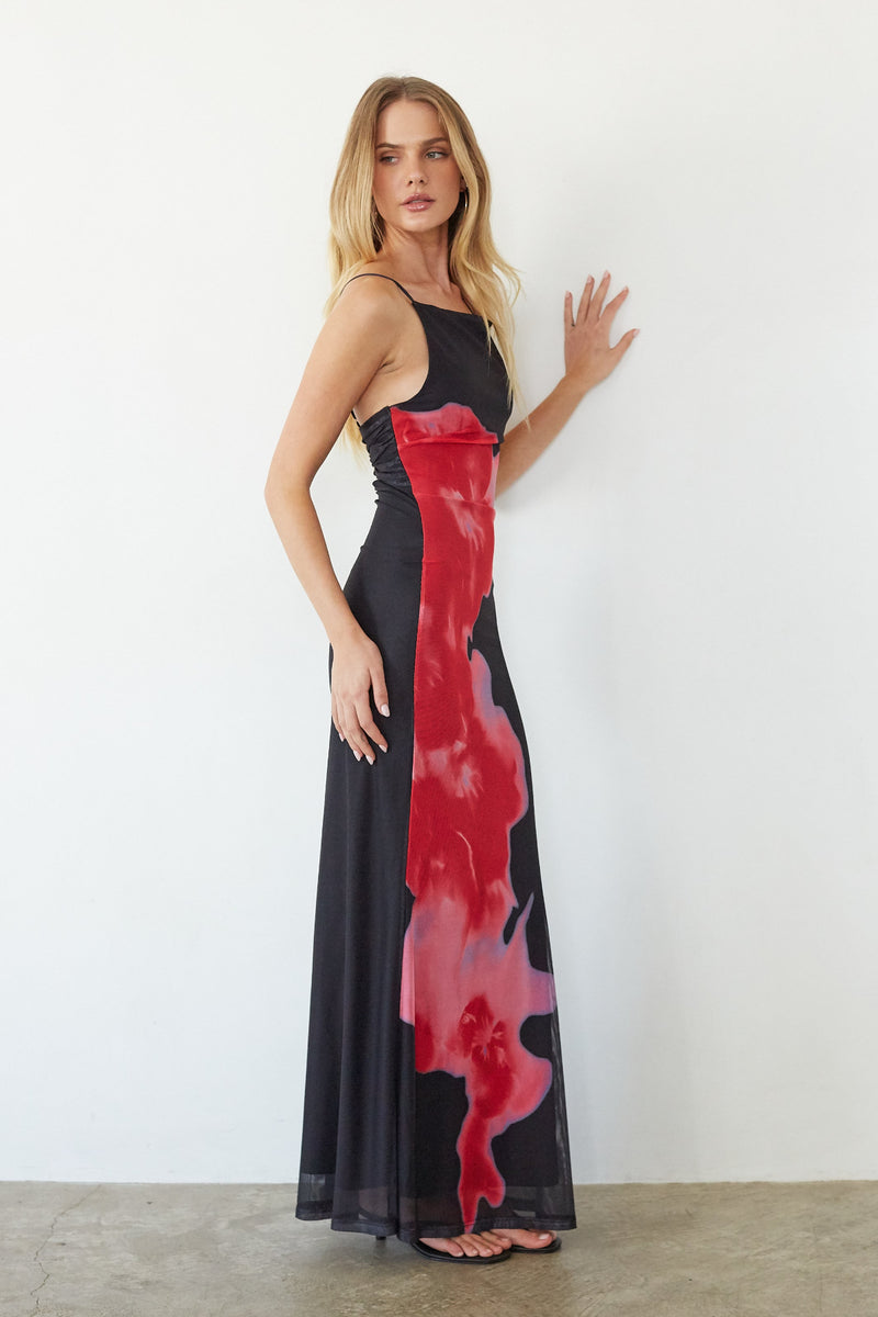 Woman wearing a black dress with red abstract patterns against a white background