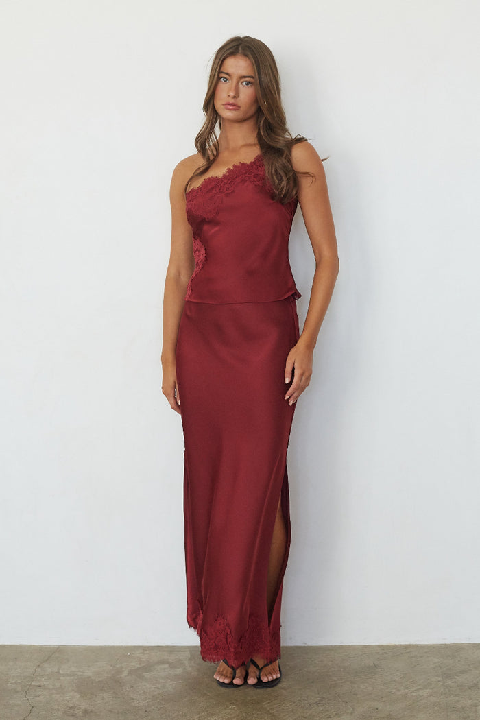 red-image | brunette model wearing a satin top and skirt with lace detailing in front of gray background