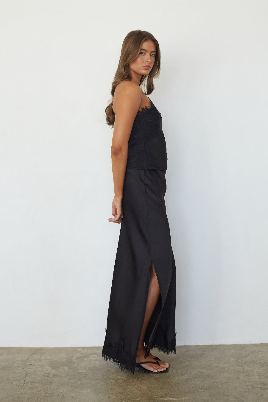 Black satin lace trim maxi skirt, side profile view showing slit detail
