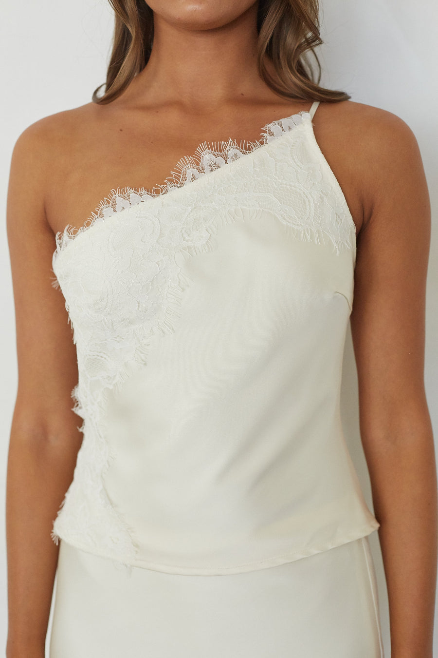 Detail close up shot of white asymmetrical top and skirt