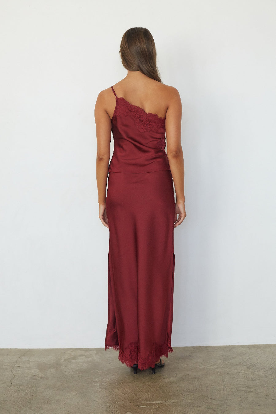 brunette model wearing a red satin lace trim top and skirt