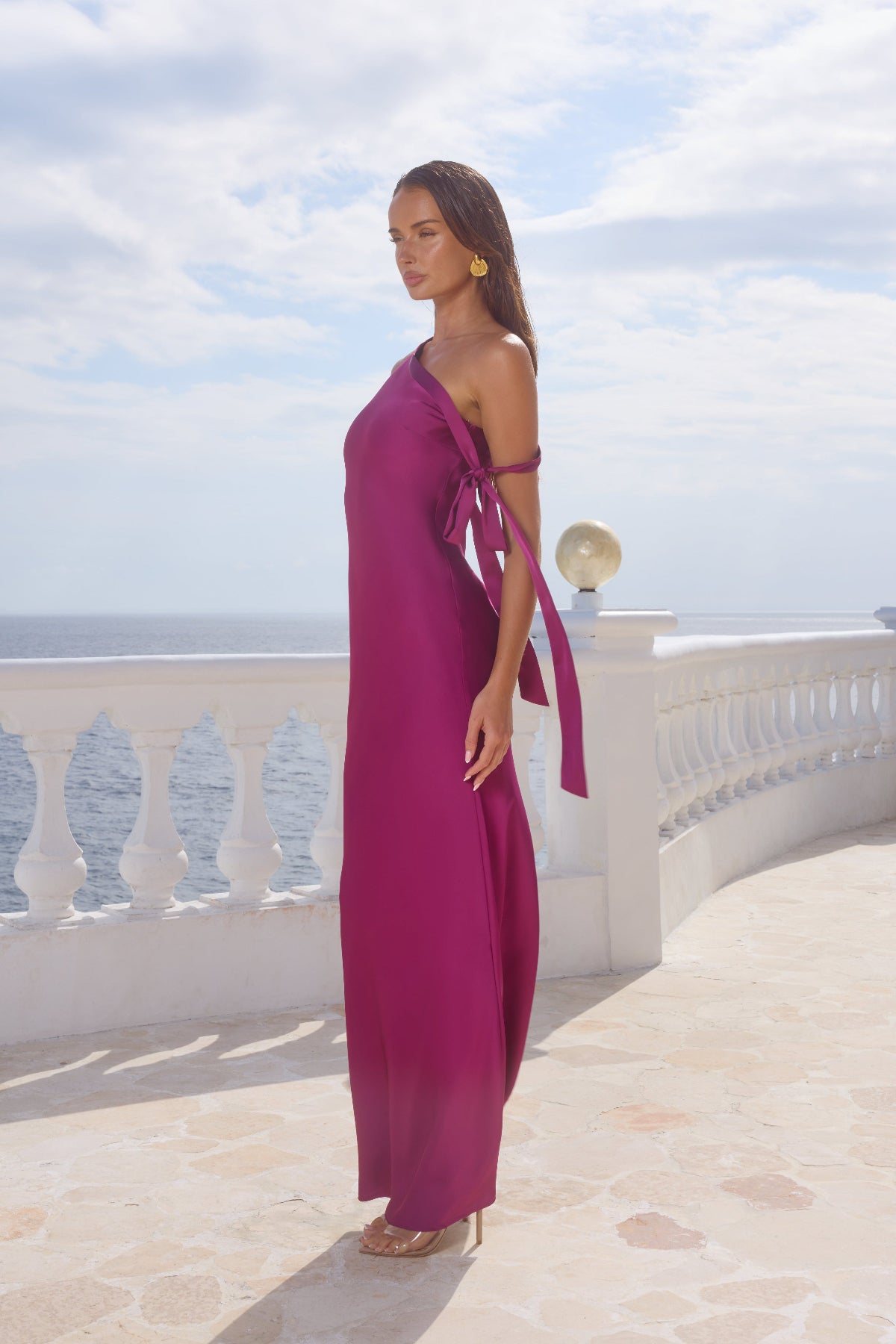 Woman in a magenta dress standing on a balcony with a scenic background
