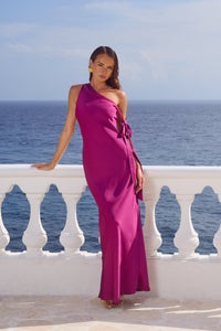 pink-image | Woman in a magenta one-shoulder dress standing on a balcony with ocean view