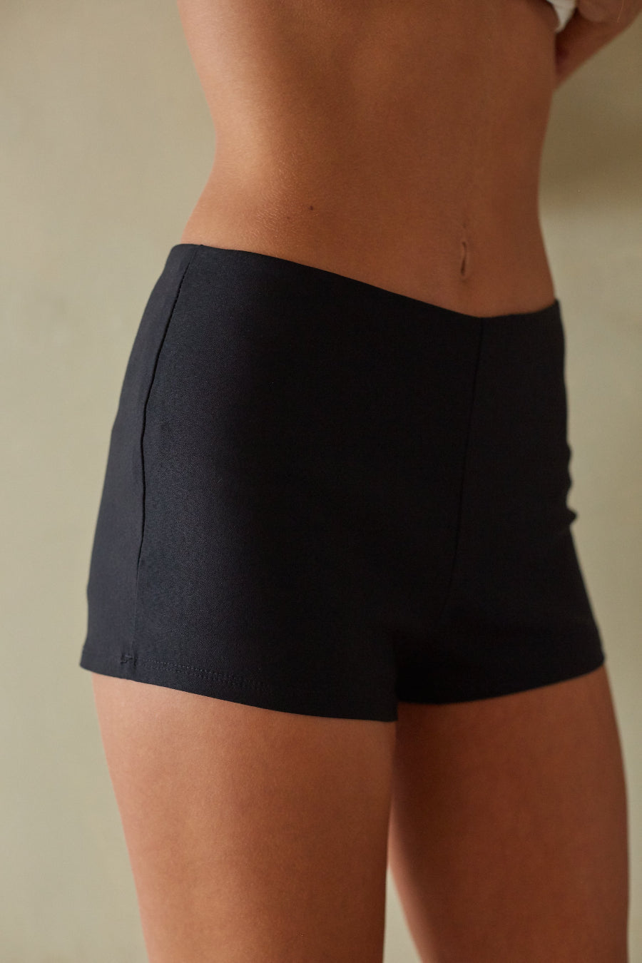 Person wearing black shorts against a neutral background