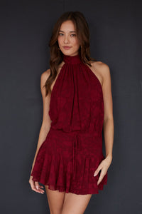 red-image | Woman wearing a burgundy halter dress against a dark background