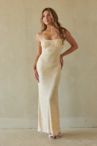 yellow-image | Woman wearing a long, light-colored dress against a plain wall.