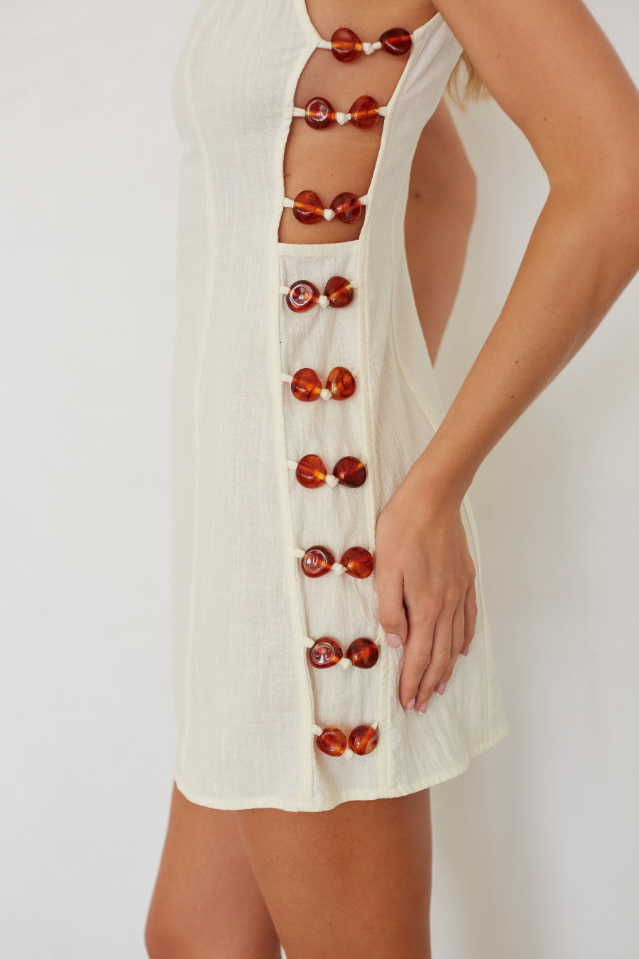 White dress with red button details on a white background