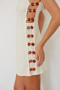 White dress with red button details on a white background