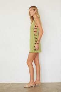 Woman wearing a green dress with button details against a white background