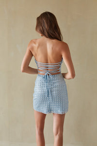 Woman wearing a light blue patterned dress with a beige background