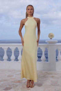 Woman in a yellow dress standing on a balcony with ocean view