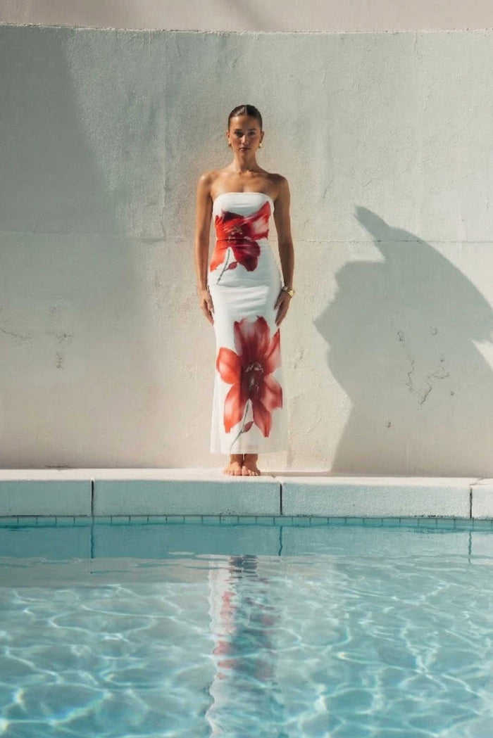 Woman in a floral dress standing by a pool with a neutral background