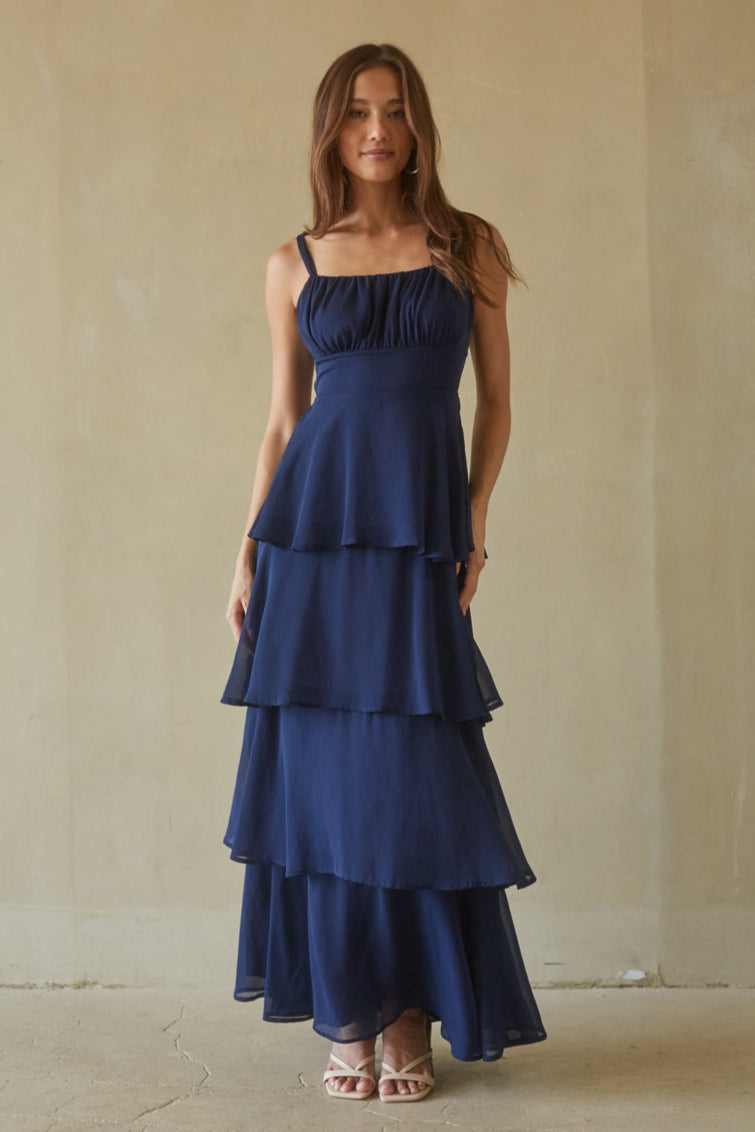 blue-image | Woman wearing a navy blue tiered dress against a plain background
