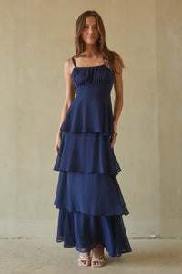 blue-image | Woman wearing a navy blue tiered dress against a plain background