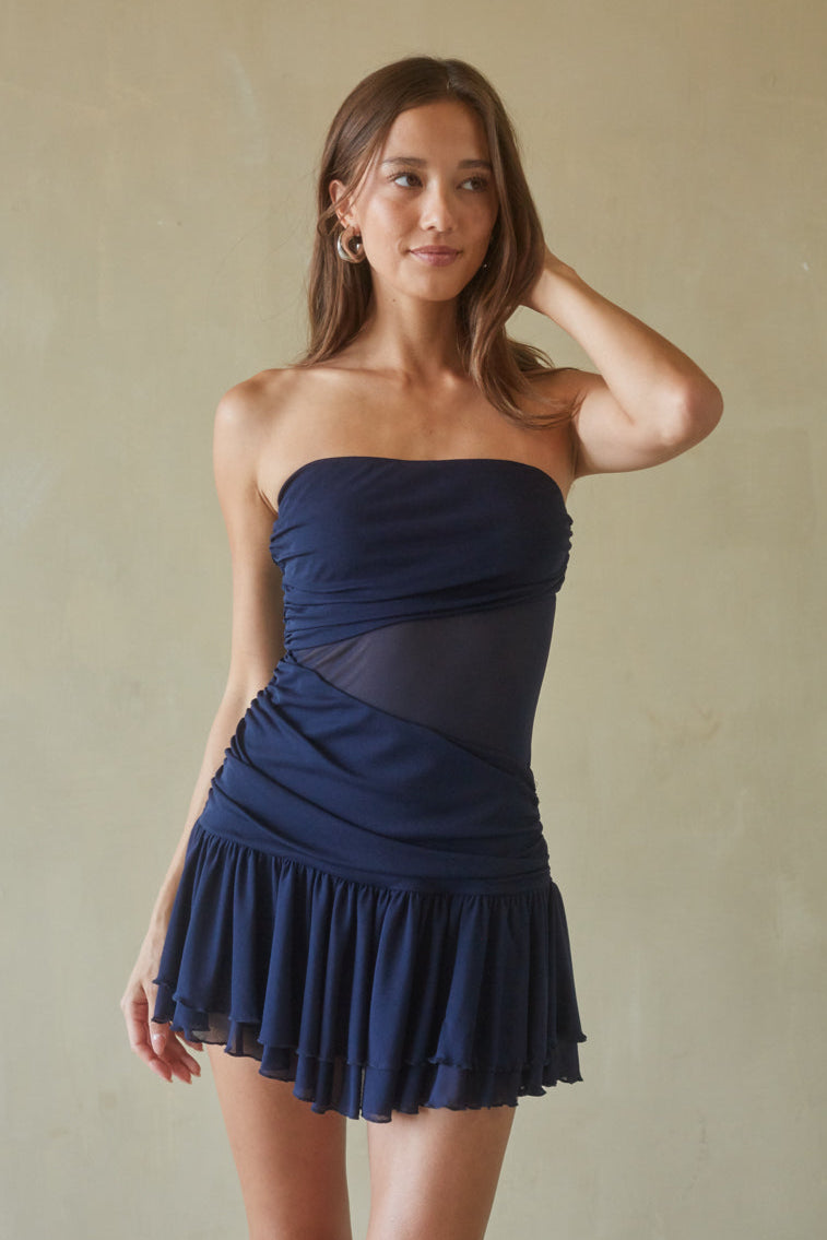 blue-image | Woman wearing a strapless navy blue dress against a plain background