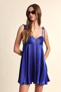 Woman wearing a blue dress with sunglasses on a beige background