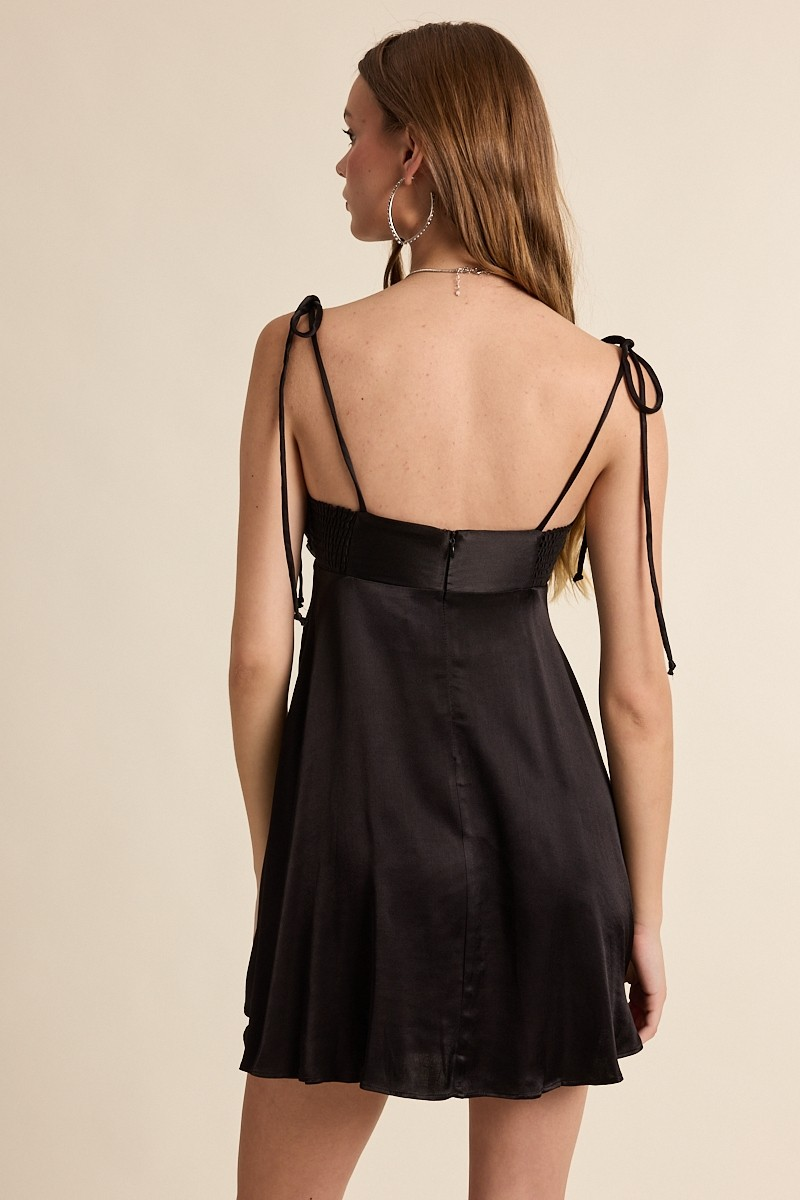 Black dress with thin straps on a beige background