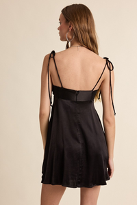 Black dress with thin straps on a beige background