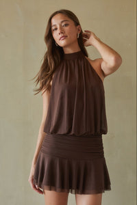 brown-image | Woman wearing a brown sleeveless top and skirt against a beige background