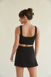 Fitted black activewear skort with side slit and built-in shorts with pockets and smoothing fabric