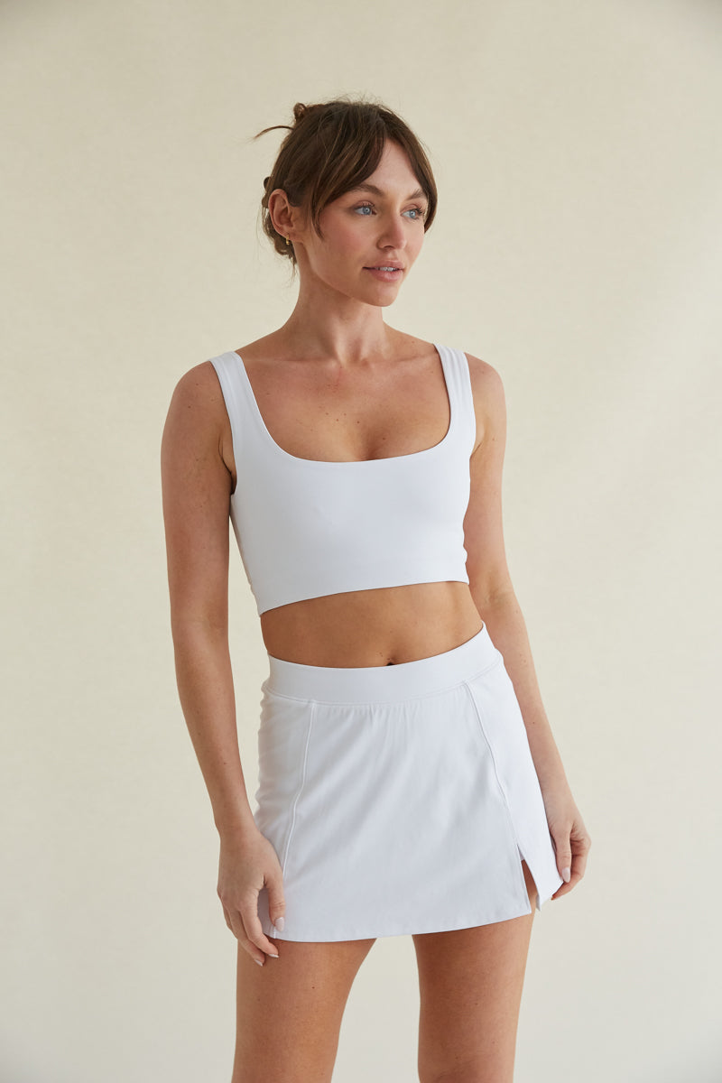 Fitted white tennis skort with side slit and built-in shorts with pockets