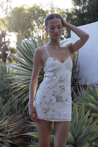 white-image | Woman wearing a white sequin dress standing outdoors with plants in the background