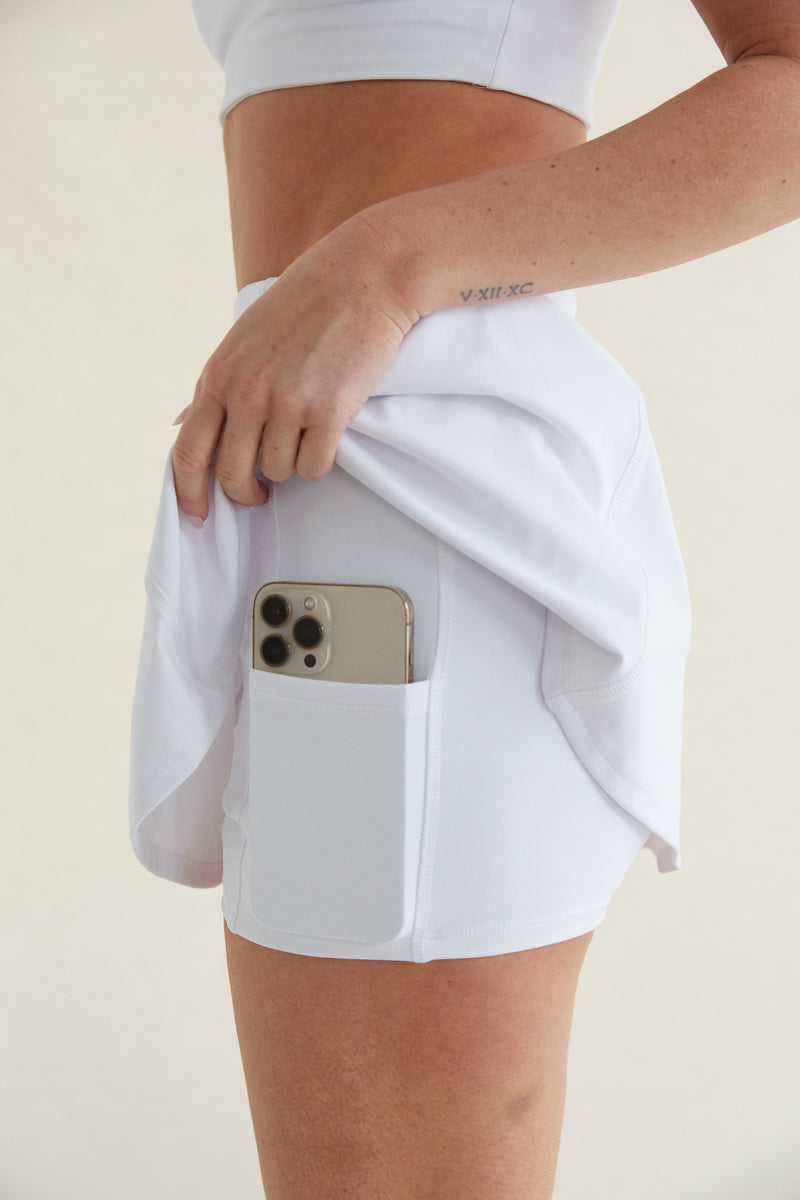 White high-waisted fit and flare tennis skort with built in shorts with pockets